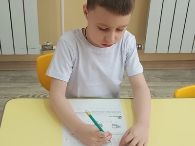 Ребенок сосредоточенно проводит волнистые линии